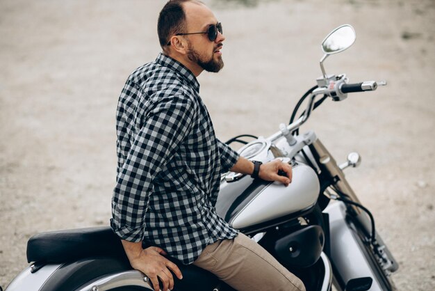 Bel homme avec sa moto dans une carrière de sable