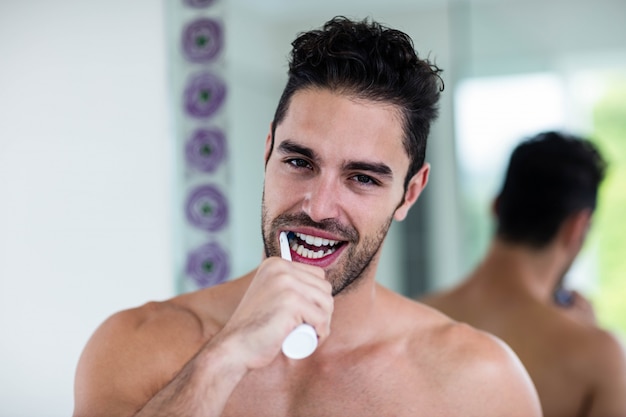 Bel homme se brosser les dents dans la salle de bain