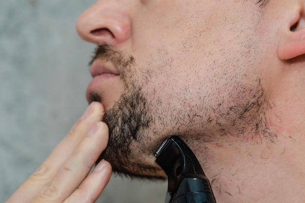 Un bel homme se rasant la barbe au rasoir électrique Hygiène du matin