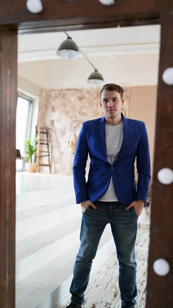 Un bel homme se regarde dans le miroir Une vue latérale d'un jeune homme dans un miroir dans une chambre moderne