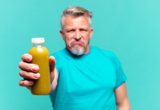 Bel homme senior buvant un smoothie végétalien