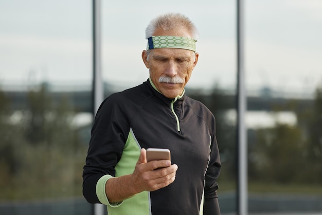 Bel homme senior sportif à l'aide de smartphone