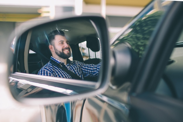 Bel homme sérieux élégant conduit une voiture.