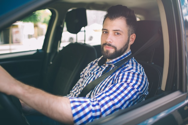 Bel homme sérieux élégant conduit une voiture.