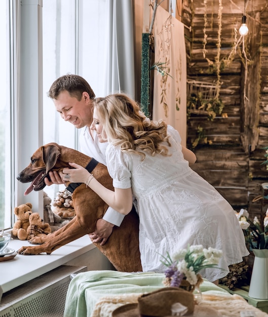 bel homme et son chien regardant par la fenêtre de son appartement. le concept de l'attente