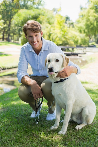 Bel homme avec son labrador dans le parc, souriant à la caméra