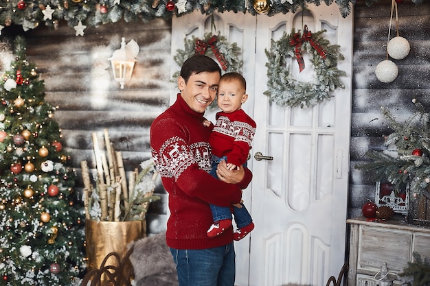 Bel homme et son mignon petit garçon posant sur l'intérieur de Noël.