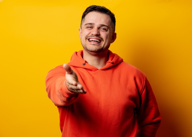 Bel homme souriant à capuche sur mur jaune