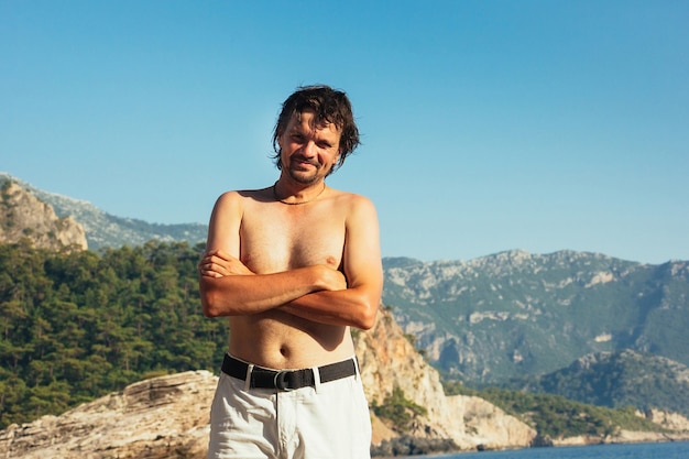 Bel homme souriant debout sur les montagnes de la plage et la mer en arrière-plan journée ensoleillée