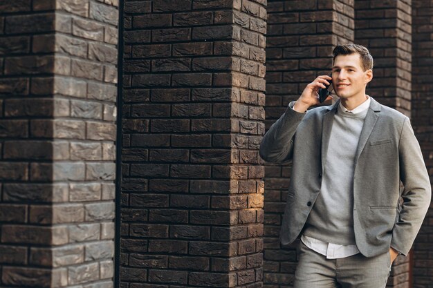 Bel homme souriant moderne marchant dans la rue et parlant au téléphone