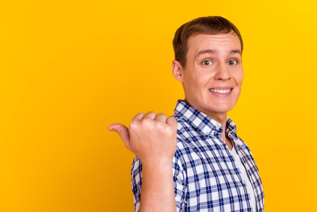 Bel homme souriant pointant vers l'espace vide promo isolé sur fond jaune