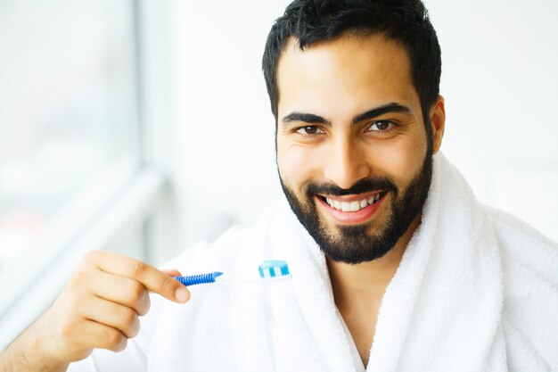 Bel homme souriant se brosser les dents blanches saines avec une brosse. Image haute résolution