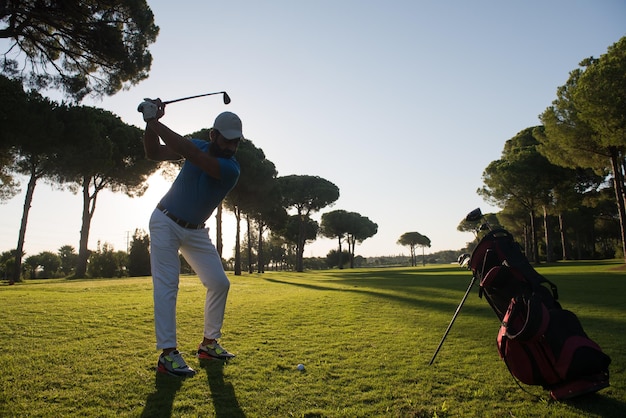 bel homme sportif, joueur de golf frappant avec un club sur le parcours au beau matin