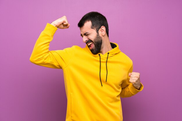 Bel homme avec un sweat-shirt jaune célébrant une victoire