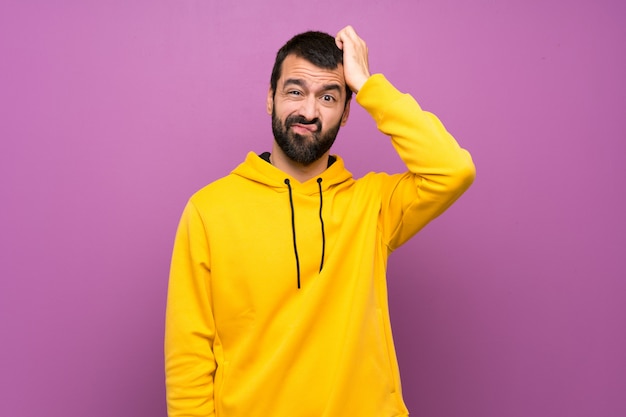 Photo bel homme avec un sweat-shirt jaune avec une expression de frustration et de non compréhension