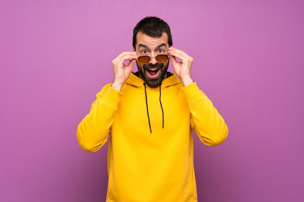 Bel homme avec un sweat-shirt jaune avec des lunettes et surpris