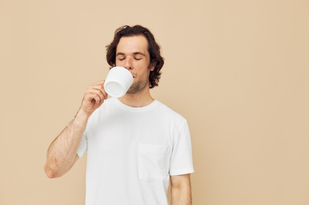 Bel homme avec une tasse blanche dans ses mains émotions posant fond isolé