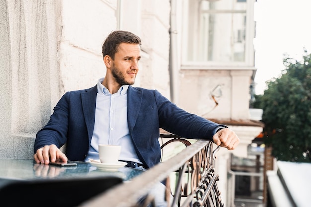 Bel homme avec une tasse de café au café. Mode de vie matinal du mâle.