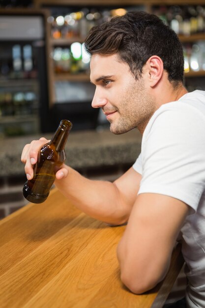 Bel homme tenant une bouteille de bière