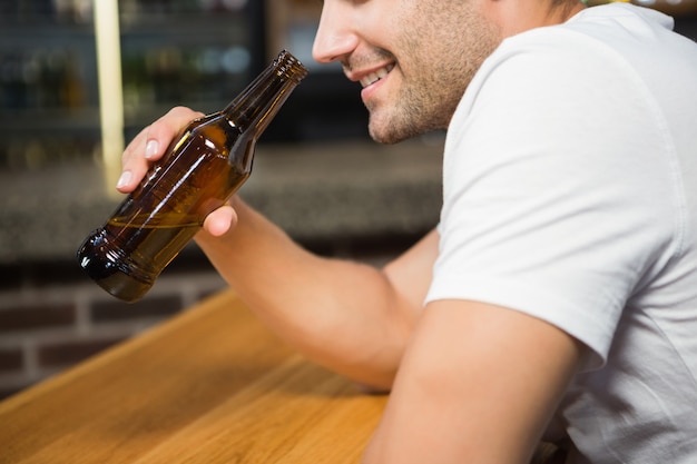 Bel homme tenant une bouteille de bière