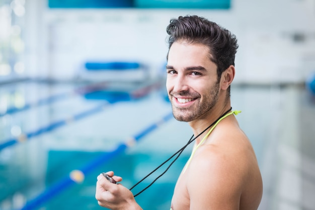 Bel homme tenant chronomètre à la piscine