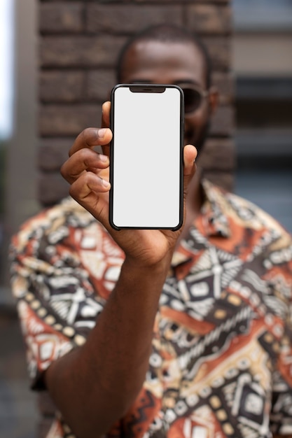 Photo bel homme tenant un smartphone avec écran blanc