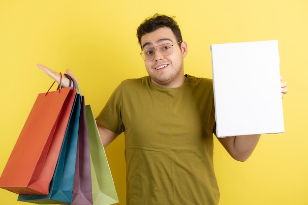 bel homme tenant une toile vide et des sacs à provisions.