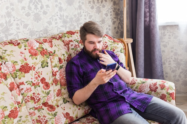 Bel homme textos avec son smartphone dans le salon