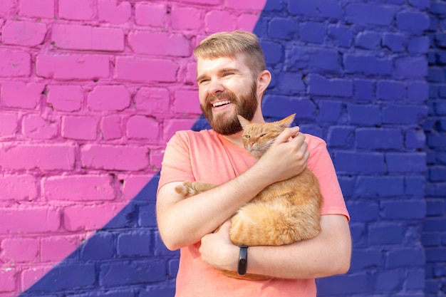 Bel homme tient et étreint un chat mignon à l'extérieur.