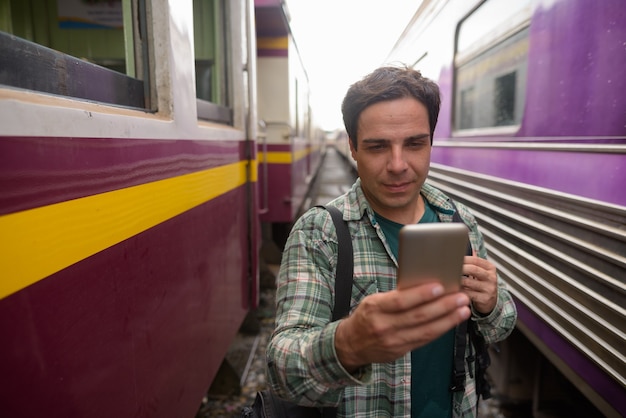 Bel homme de touriste persan à l'aide de téléphone à la gare