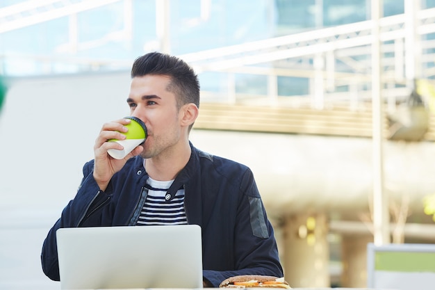 Bel homme travaillant au café sur un ordinateur portable en buvant du café