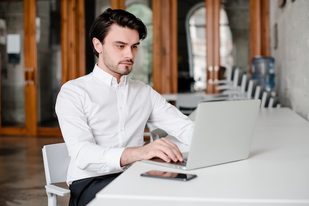 Bel homme travaillant avec un ordinateur portable au bureau