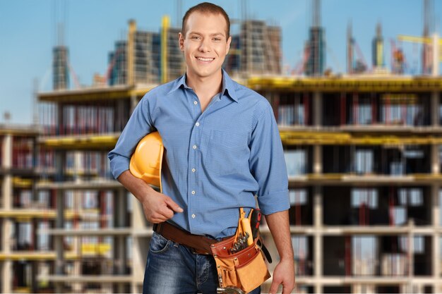 Bel homme travailleur avec ceinture à outils sur fond