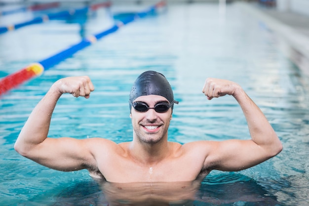 Bel homme triomphant avec les bras levés dans la piscine