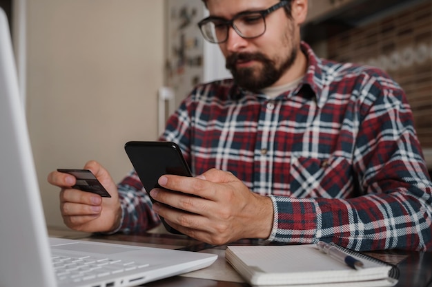 Bel homme utilisant une carte de crédit pour payer en ligne avec un smartphone