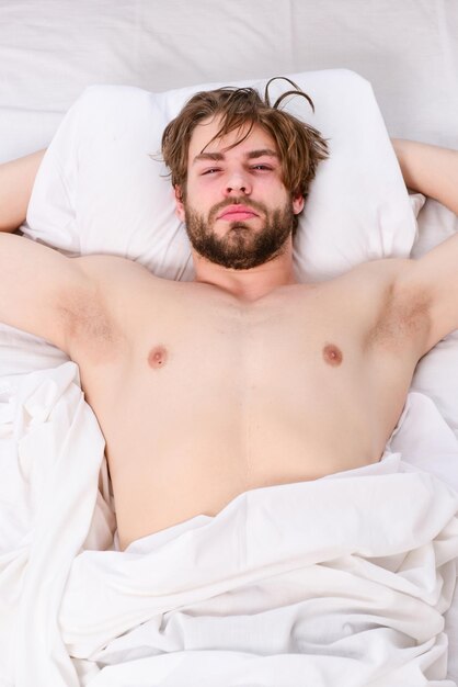 Bel homme utilisant une horloge dans son lit après s'être réveillé le matin