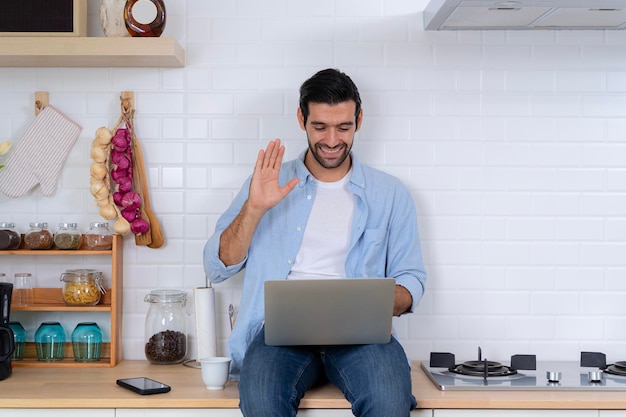 Bel homme utilisant un ordinateur portable dans la cuisine appelant une formation en ligne sur le webinaire d'affaires à l'intérieur étudiant en ligne