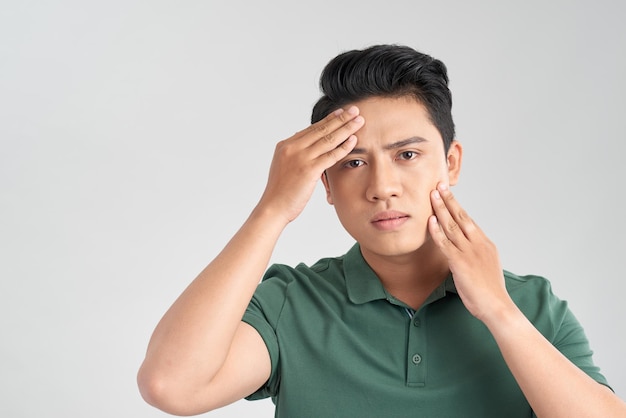 Bel homme vérifiant sa peau dans le miroir