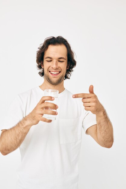 Bel homme verre d'eau dans ses mains émotions posant fond beige