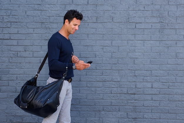 Bel homme voyageant avec sac et téléphone portable