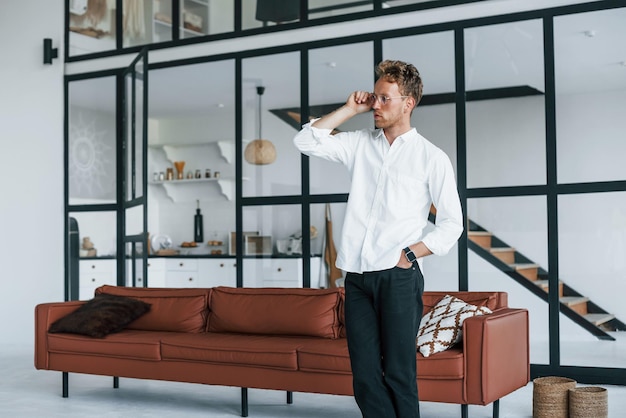 Bel intérieur caucasien jeune homme en chemise blanche élégante à l'intérieur à la maison