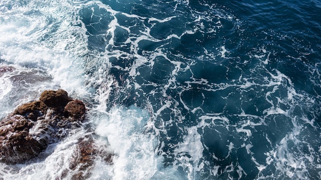 Bel océan bleu avec vagues et vue de dessus de falaise rocheuse