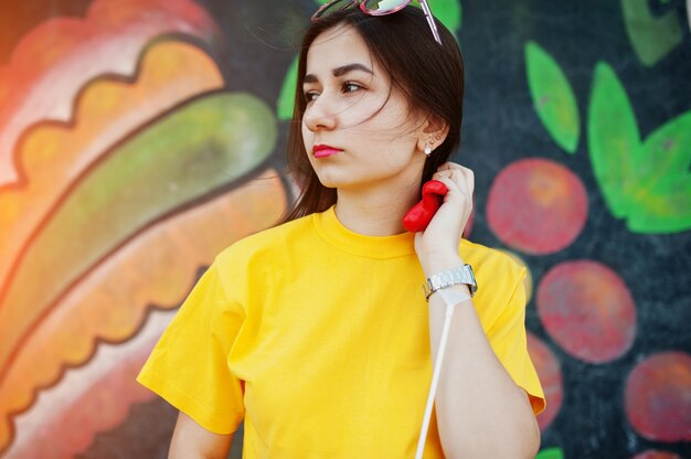 Belle adolescente au t-shirt jaune près du mur de graffitis.