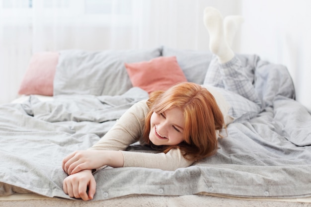 Belle adolescente blonde sur lit à la maison