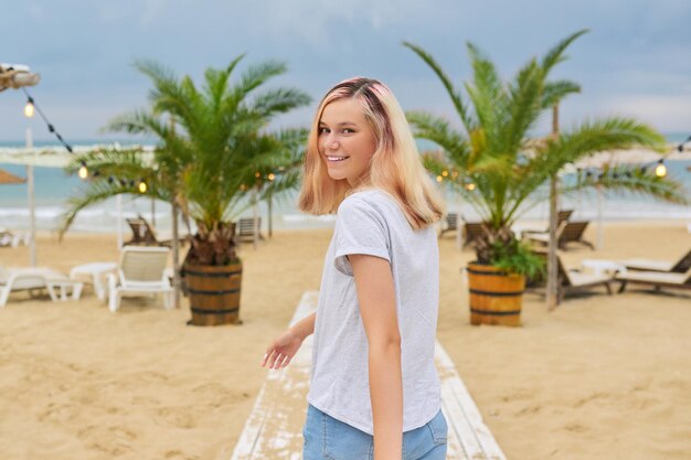 Belle adolescente blonde modèle sur la plage du soir