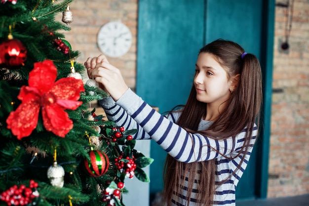 Belle adolescente décore le sapin de Noël à la maison.