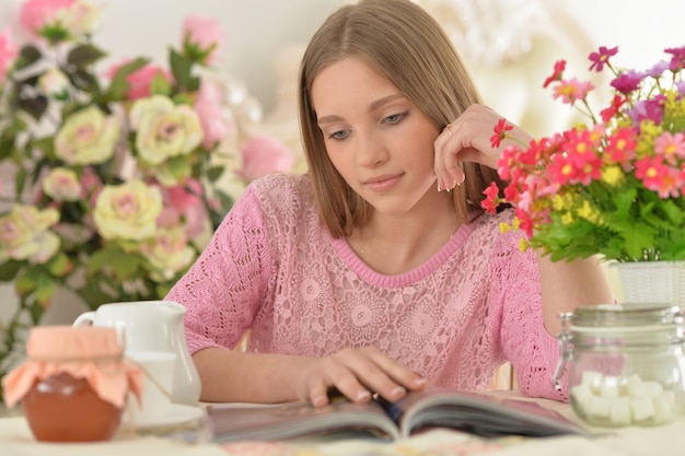 Belle adolescente lisant un magazine à la maison