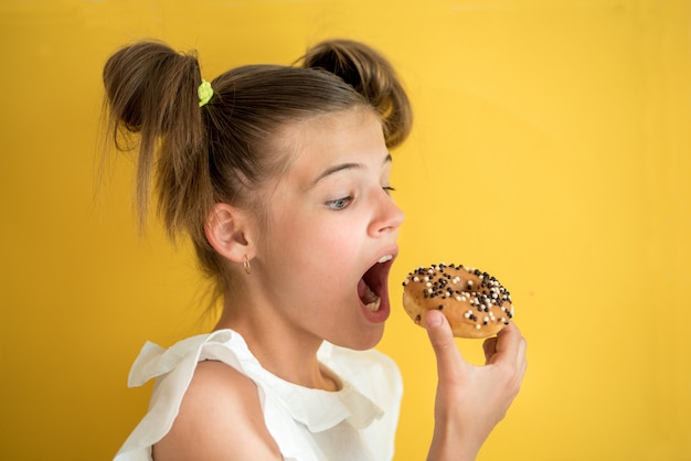 Belle adolescente mangeant un beignet.