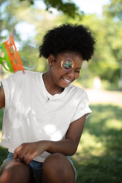 Photo belle adolescente noire jouant avec des bulles de savon