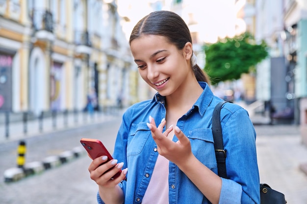 Belle adolescente parlant à l'aide d'un fond urbain de smartphone